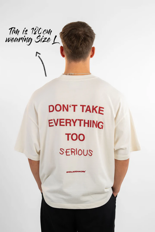 Rückansicht eines weißen T-Shirts mit rotem Rückendruck „DON’T TAKE EVERYTHING TOO SERIOUS“. Der Mann trägt Größe L bei 180 cm Körpergröße.