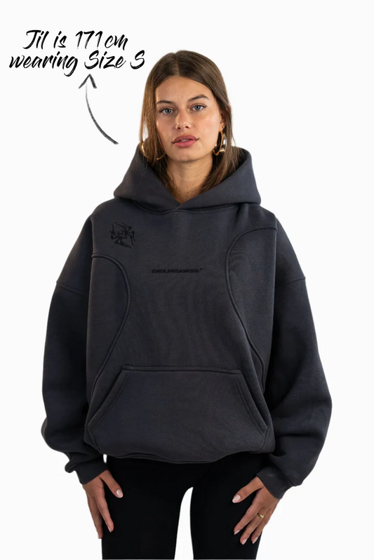 Schwarzer Oversized-Hoodie mit Herzlinien-Stickerei und schwarzem „ENDLESSAMORE®“-Logo auf der Brust sowie grafischem Schulterprint. Getragen von Jil (171 cm) in Größe S.