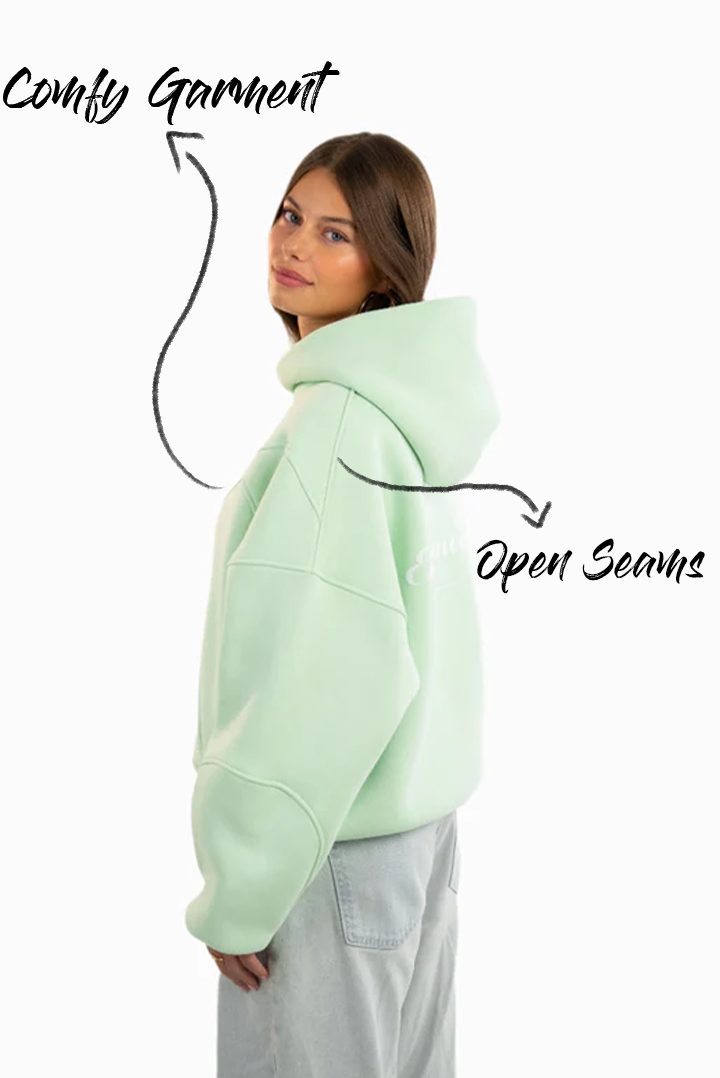 Seitenansicht des Hoodies mit offener Nahtführung, getragen von einem weiblichen Model.