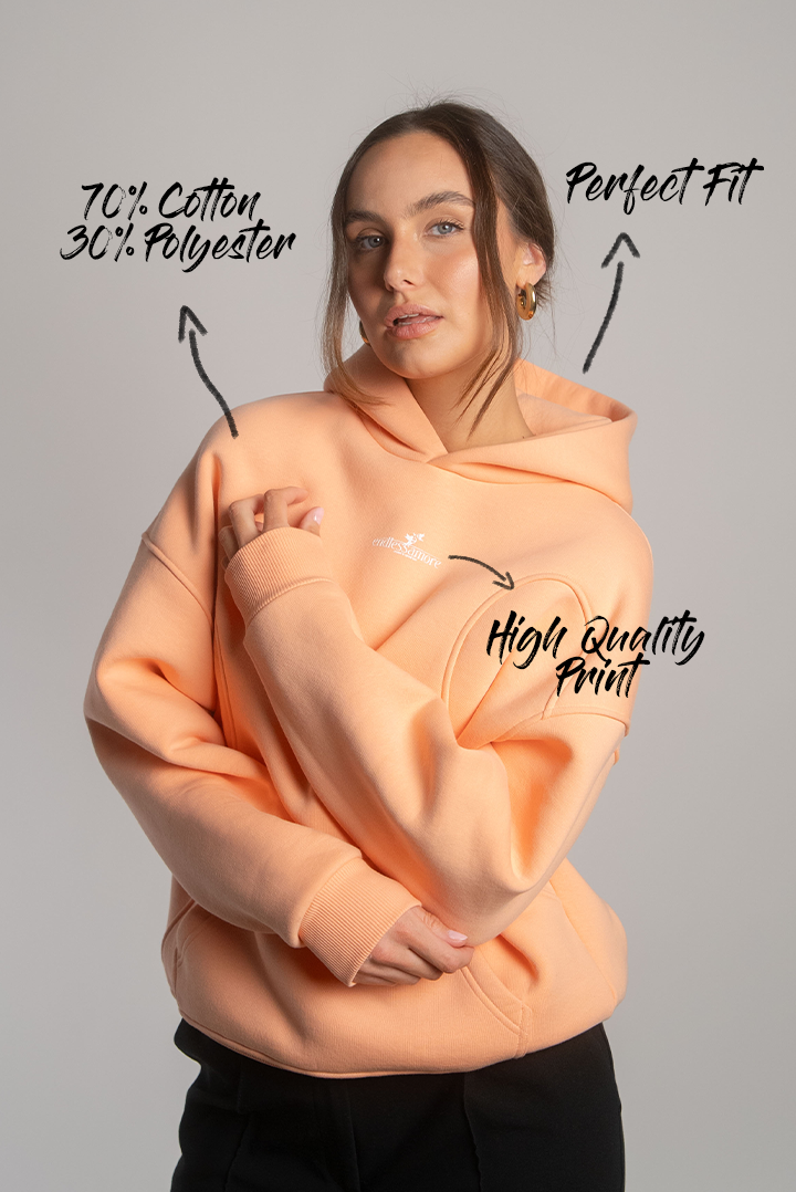 Apricotfarbener Hoodie mit weißem Brustlogo „endlessamore – created to spread love“, getragen von Frau frontal gezeigt.