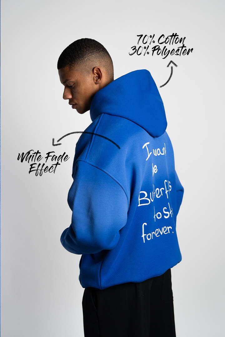 Seitlicher Blick auf den royalblauen Hoodie mit Farbverlauf, Materialhinweis (70 % Baumwolle, 30 % Polyester) und weißem Schriftzug auf dem Rücken.