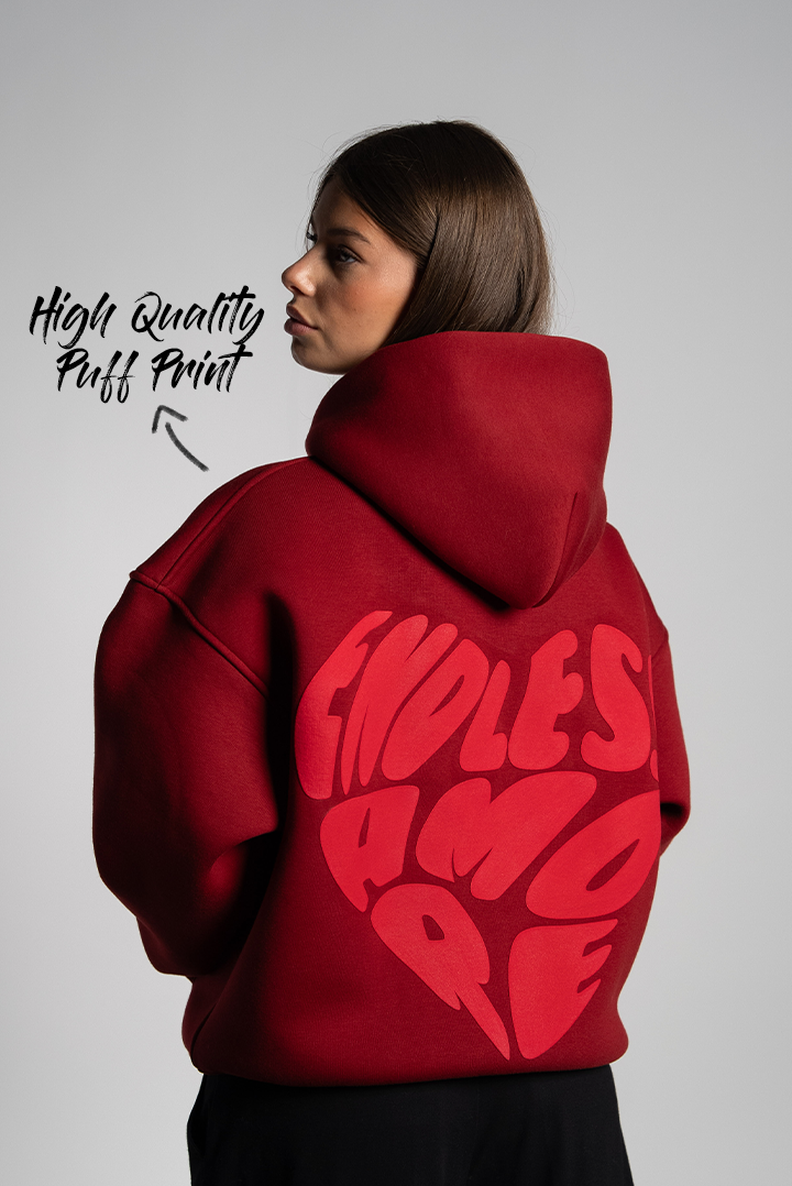 Rückansicht der Frau im Hoodie mit großem roten „ENDLESS AMORE“-Print in Herzform auf dem Rücken. Der Druck ist als Puffprint hervorgehoben.