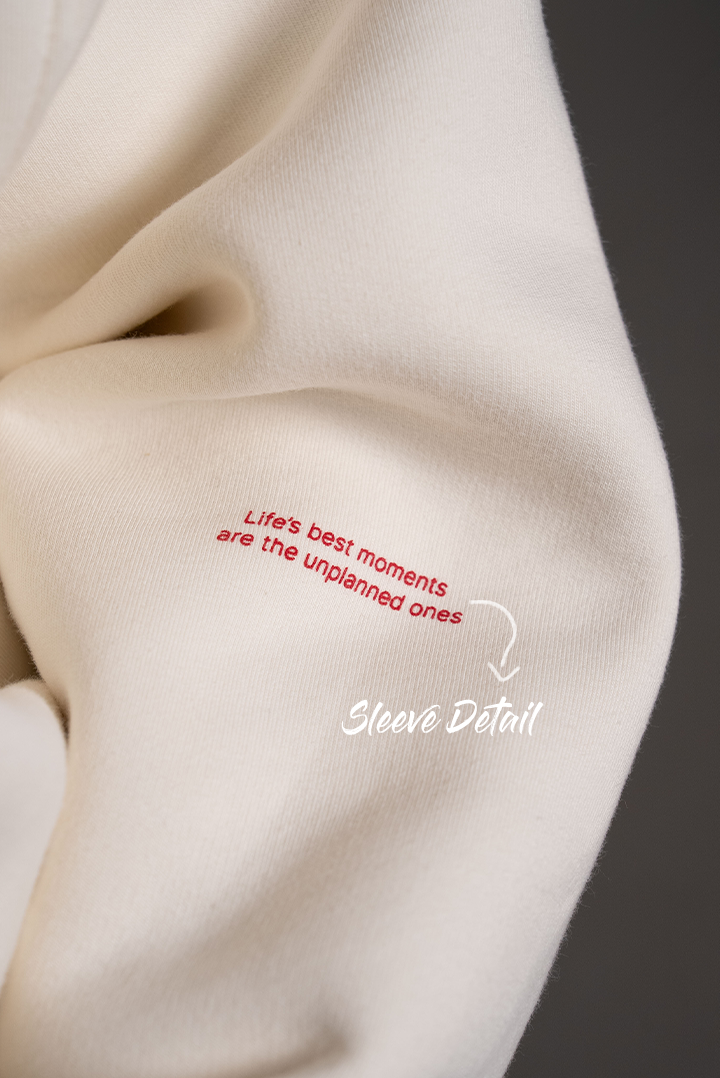 Detailaufnahme des Ärmels. Zu lesen ist der rote Aufdruck „Life’s best moments are the unplanned ones“ in kleiner Schrift. Ein Pfeil weist auf den Bereich „Sleeve Detail“ hin.