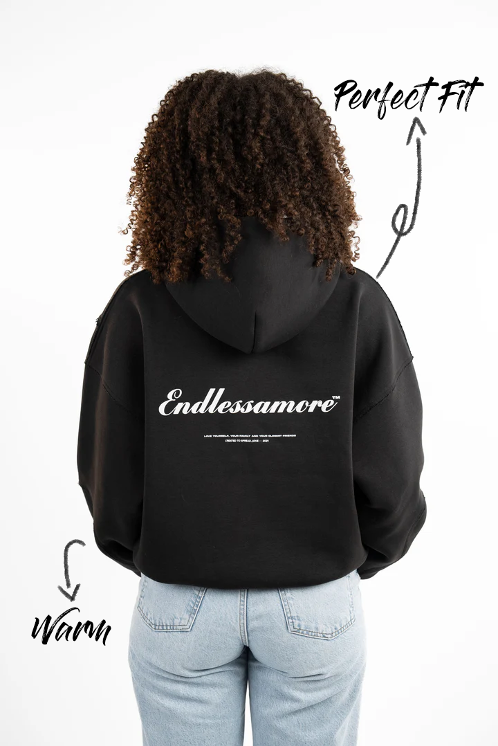 Schwarzer Kapuzenpullover mit weißem Schriftzug „Endlessamore“ auf dem Rücken. Die Passform ist locker, die Nähte betont und der Stoff wirkt dick und warm.