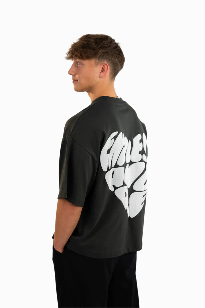 Schwarzes Oversized-T-Shirt mit großem weißen Rückendruck in Herzform und dem Schriftzug „ENDLESS AMORE“. Das Model (180 cm) trägt Größe L und steht seitlich mit Blick nach hinten.
