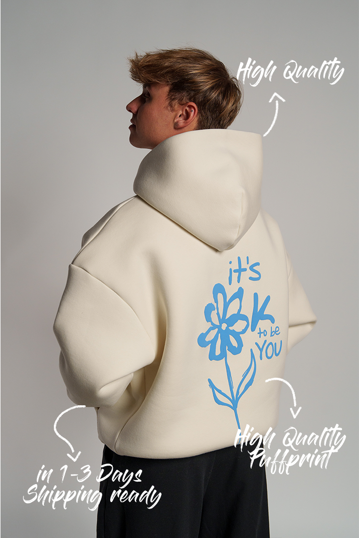 Rückseite eines weißen Hoodies mit großem, hellblauen Puffprint: stilisierte Blume mit Text „it’s OK to be YOU“.