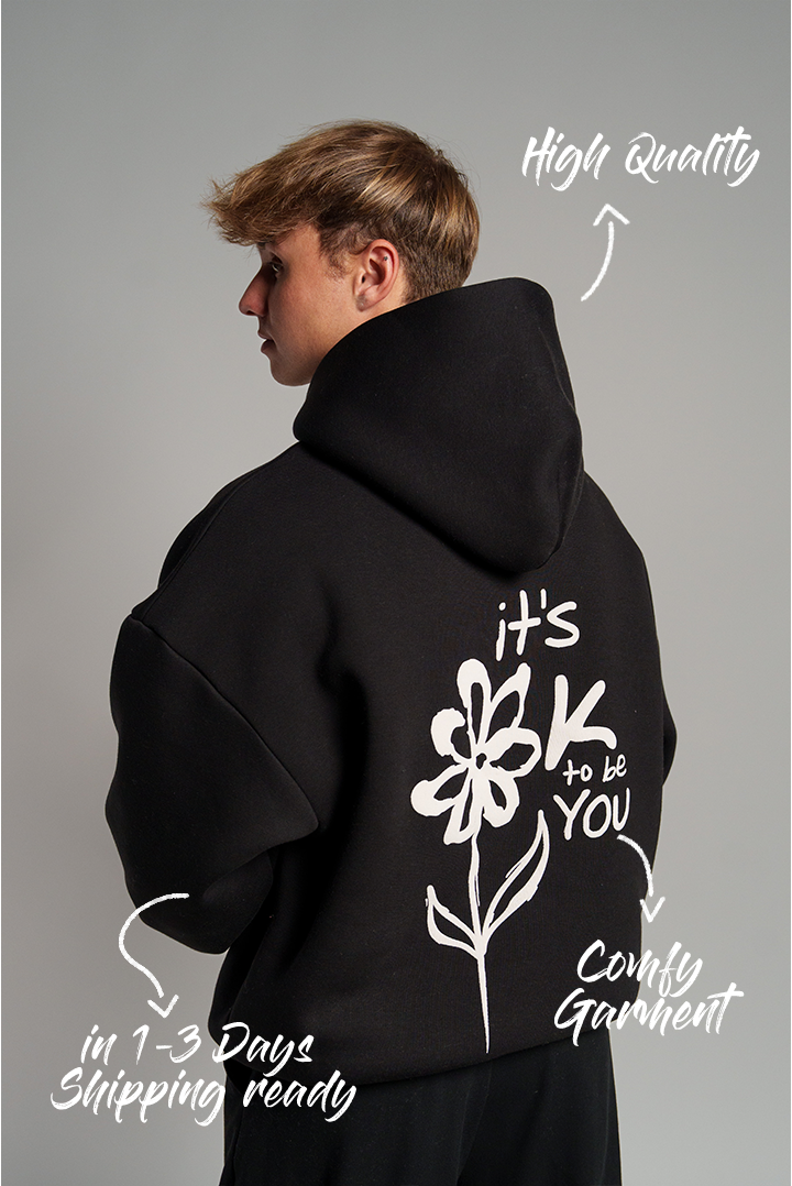 Rückseite eines schwarzen Hoodies mit großem, weißen Puffprint: stilisierte Blume mit Schriftzug „it’s OK to be YOU“.