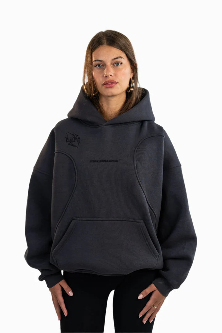 Schwarzer Oversized-Hoodie mit mittig gesticktem „ENDLESSAMORE®“-Logo, strukturierter Nahtführung und Kängurutasche. Grafik-Stickerei auf der linken Schulter. Getragen von Jil.