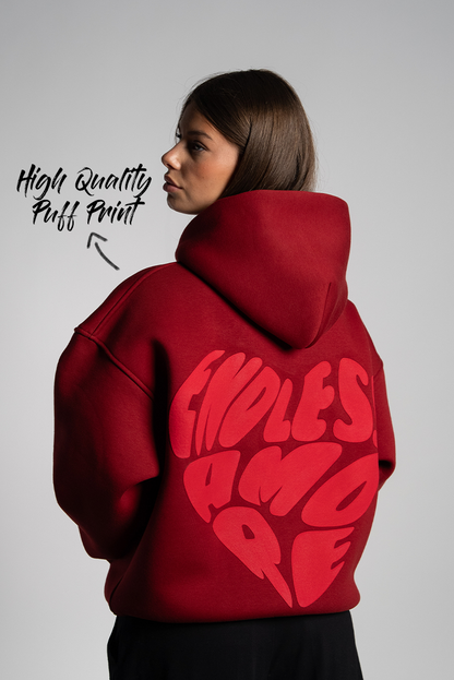 Rückansicht der Frau im Hoodie mit großem roten „ENDLESS AMORE“-Print in Herzform auf dem Rücken. Der Druck ist als Puffprint hervorgehoben.